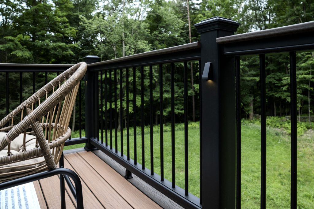 Modern black railing post with integrated LED lighting and a flat composite top rail on a new deck in Clark's Summit, PA.