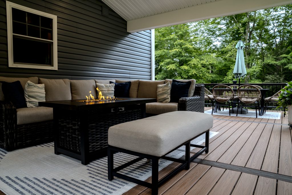 Close-up detail of a black aluminum deck railing featuring a flat composite "drink rail" top cap and a mounted LED post light in Clark's Summit, PA.