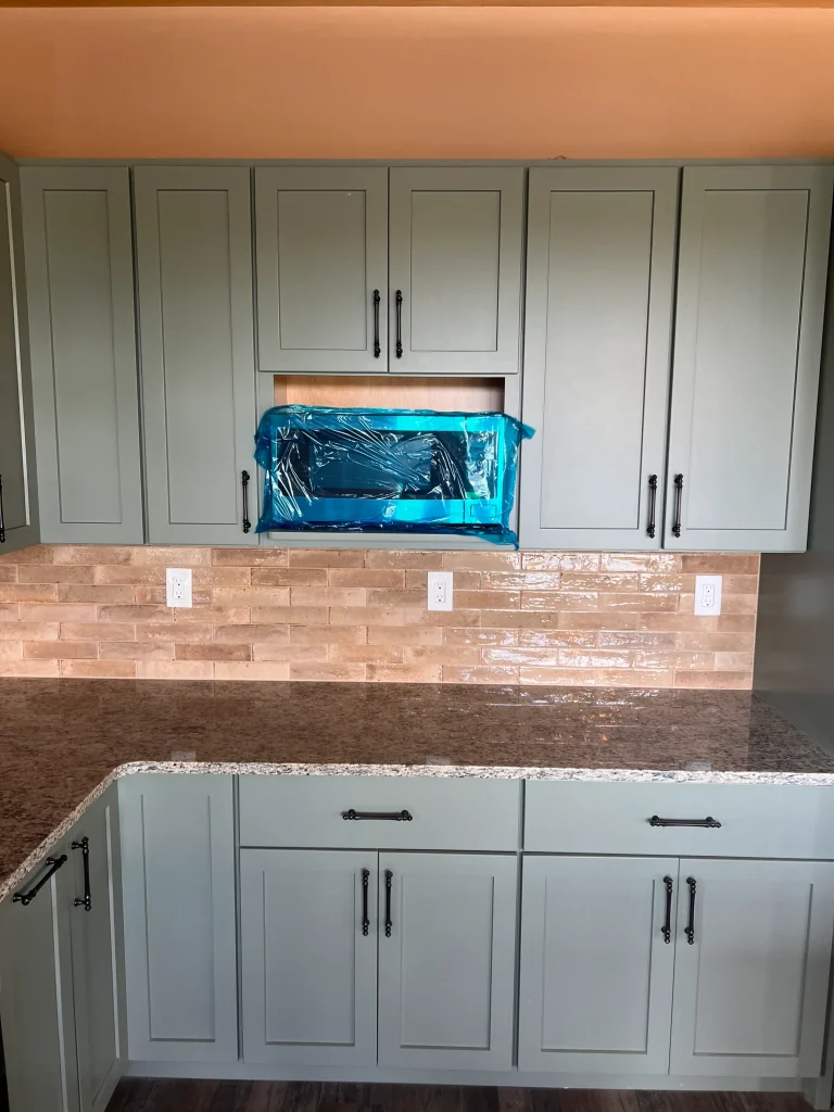 Kitchen cabinets, counter, and floating microwave installed in custom home design