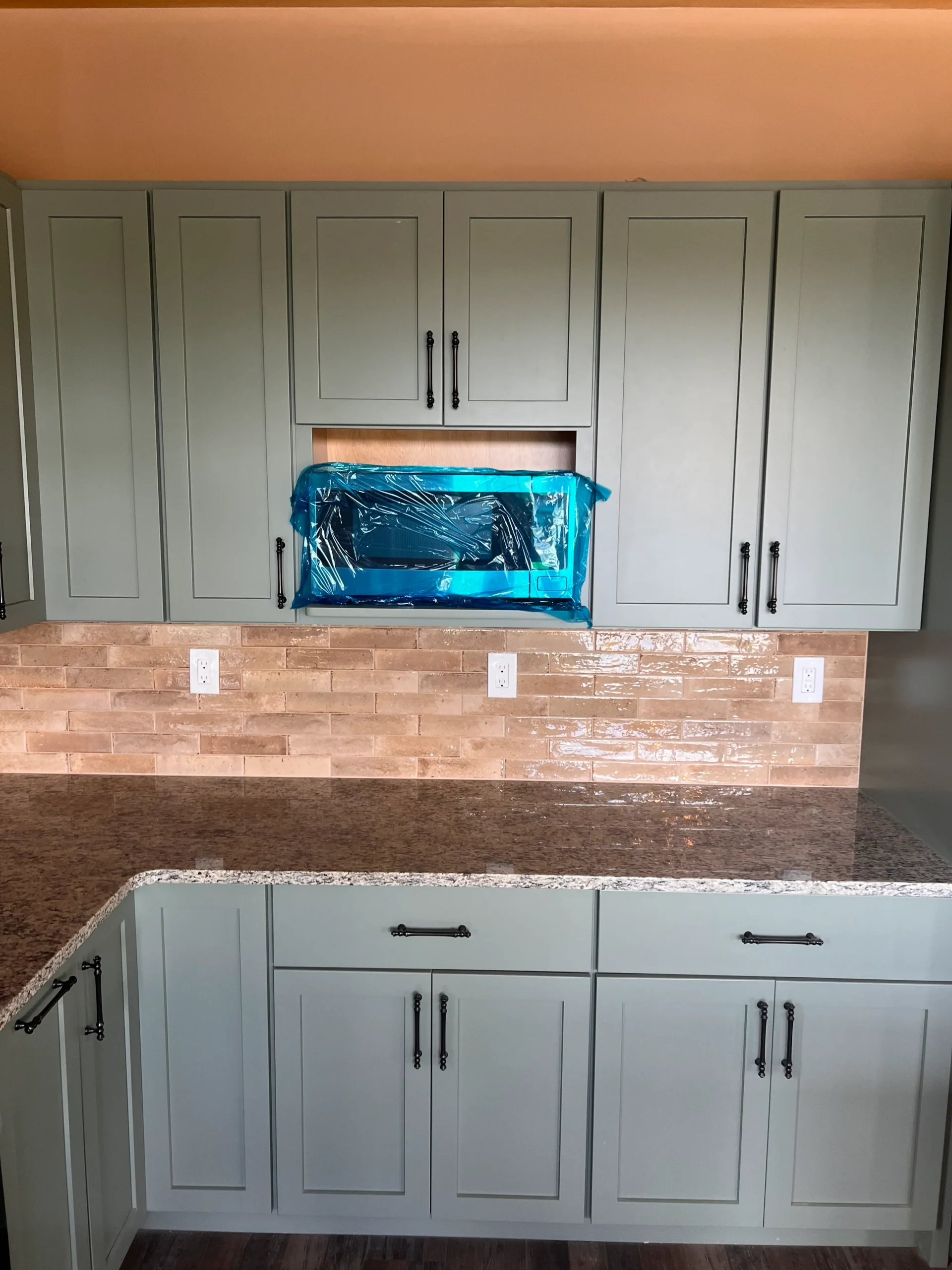 Kitchen cabinets, counter, and floating  microwave installed in custom home design