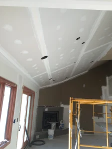 Interior view of building a new home with scaffolding set up and raw sheetrock with mudding completed at the seams.
