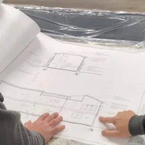 2 contractors showing the Design process for building a new home and pointing at a floorplan for a home.