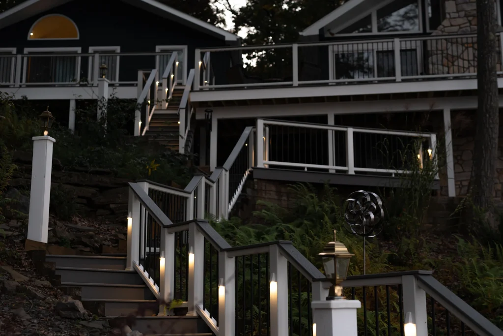 Elevated view of a completed lakefront Trex deck and patio area illuminated at night with warm TexDeck railing lights, built by NEPA builders.