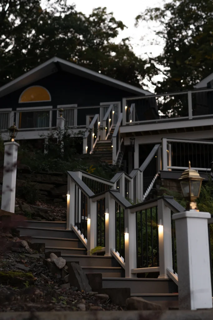 Close-up of a completed Trex deck staircase with glowing TexDeck LED post lighting at dusk, built by NEPA builders.