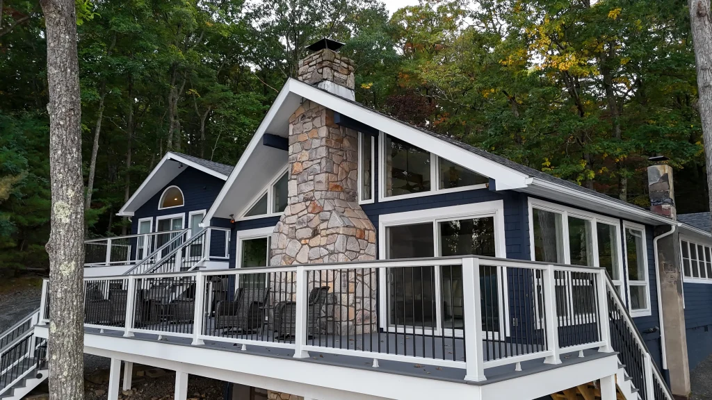 Finished Trex deck patio area with high-end TexDeck railing featuring white posts and black balusters, integrated next to a custom stone fireplace by NEPA builders.