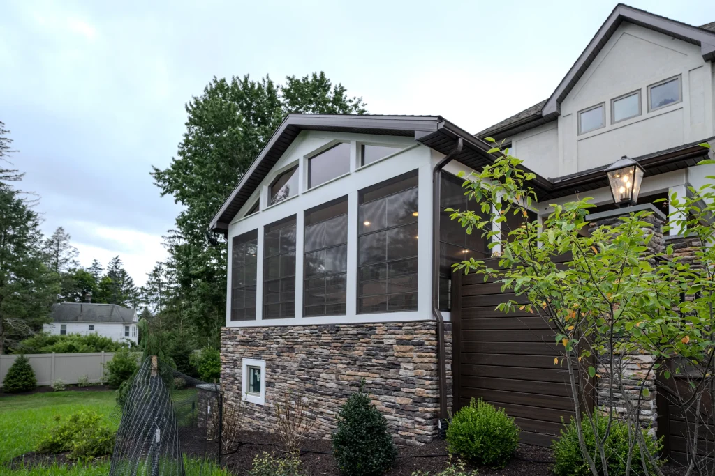 Three-season Eze-Breeze enclosed deck addition with cultured stone foundation and Board & Batten accents at a home in Dalton, PA