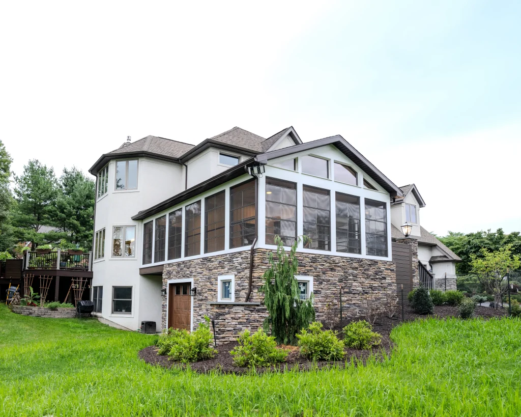 Custom three-season room and attached garage addition completed by NEPA Builders in Dalton, PA with cultured stone, large windows, and low-maintenance exterior finishes.